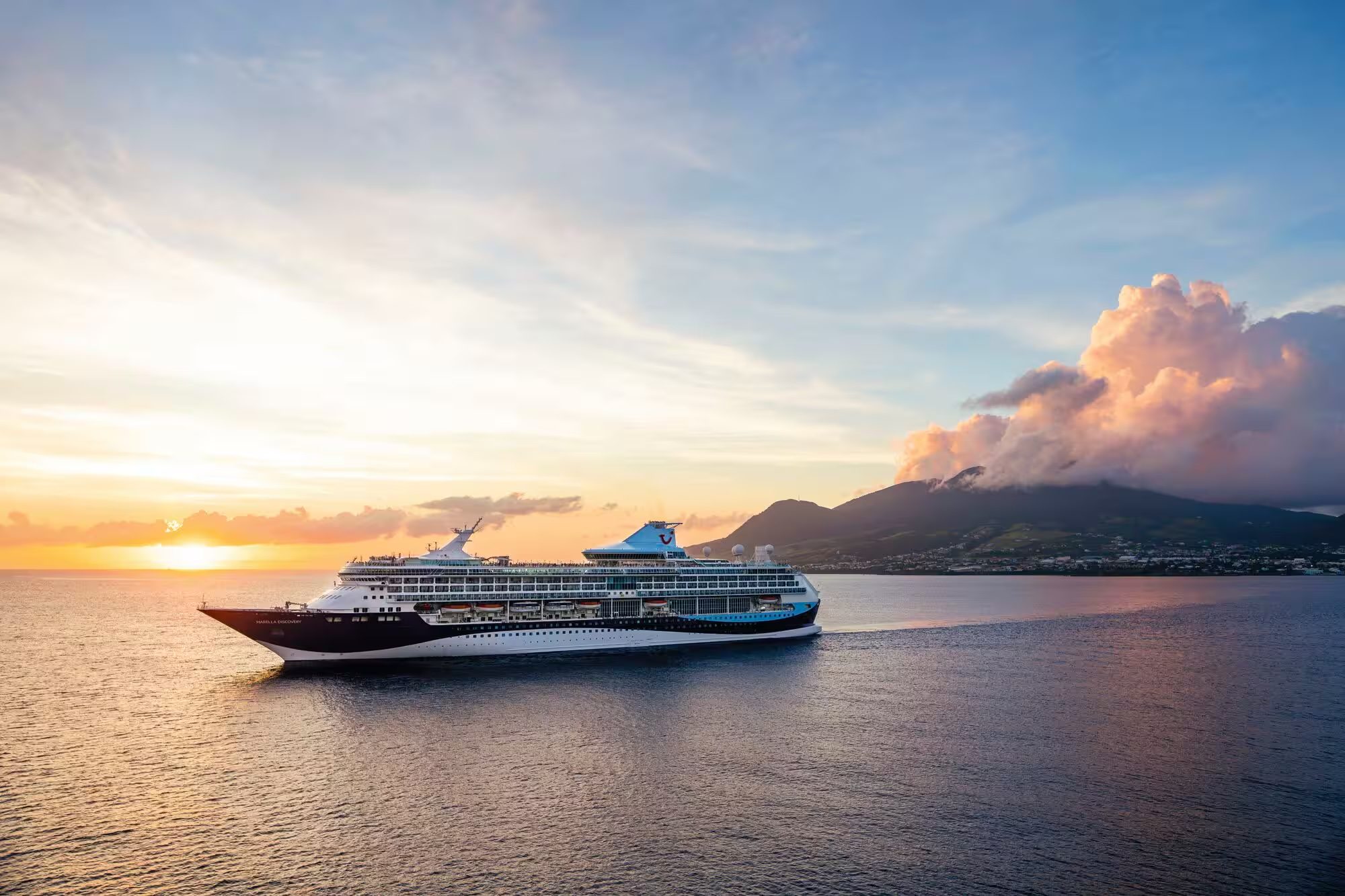 Marella cruise ship sailing past mountains at sunset