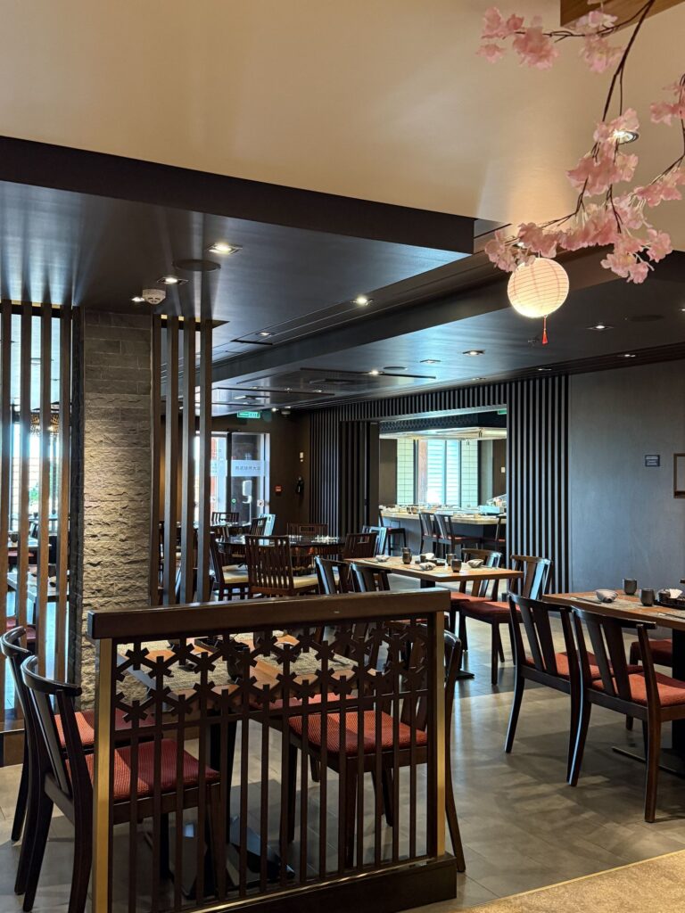 An Asian-themed restaurant aboard Genting Dream, set with tables, lanterns and floral decor.