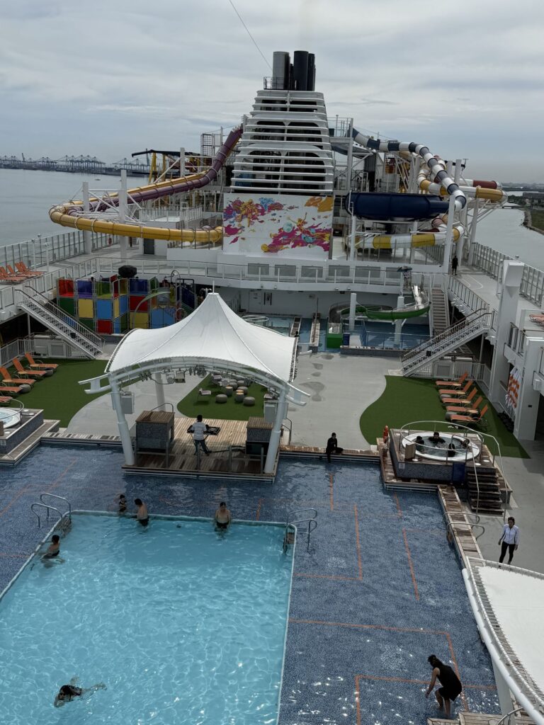 Genting Dream pool deck with multi-coloured water slides, pool and recreational areas viewed during the Jobs Kreate cruise visit.