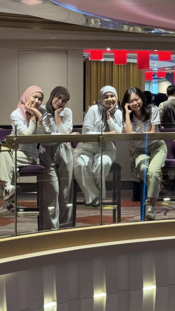 Jobs Kreate team members at a glass railing inside the Genting Dream atrium during the cruise visit.